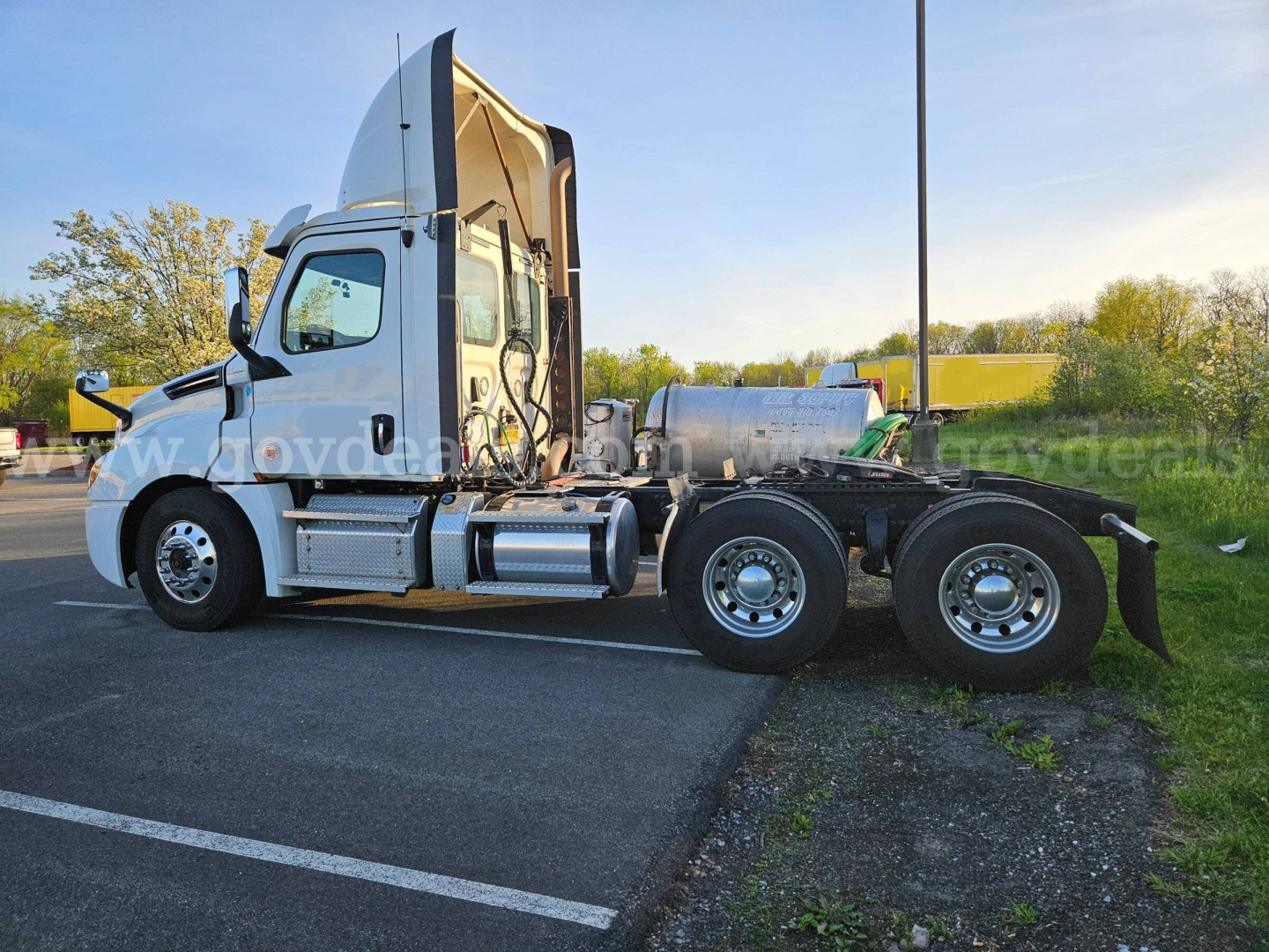 Side view of a 2020 Freightliner Cascadia tractor with cab raised, showing rear chassis and fuel/tolling tanks.