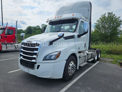 Freightliner Cascadia semi truck in a parking lot, white cab, side view showing front grille and aerodynamic mirrors.
