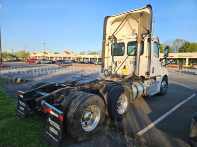 Freightliner Cascadia truck tractor in a parking lot showing its rear chassis and cab from the right side.