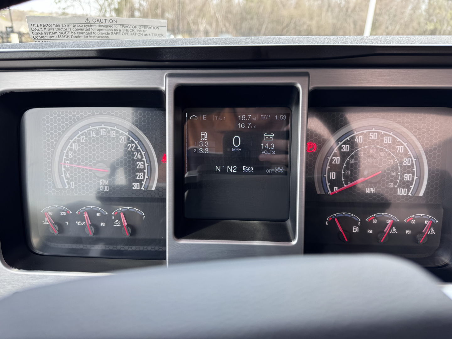 Dashboard view of a 2027 Mack PI64T truck showing instrument cluster, central display, and gauge needles.