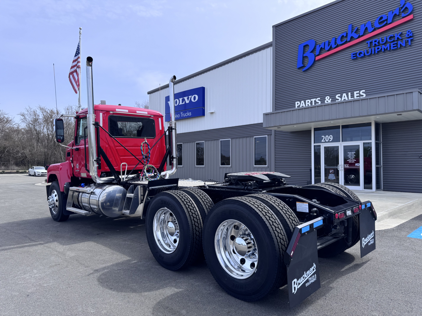 Truck chassis and cab in red, Mack PI64T, tractor tractor with dual rear axles, at Brunkens Equipment dealership.