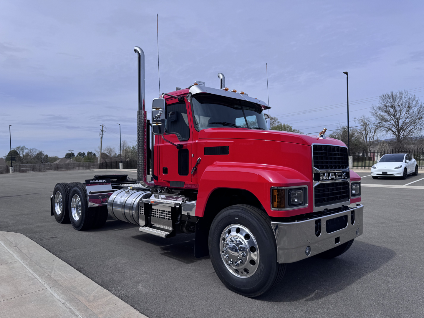Mac PI64T truck in red side view showing exhaust stacks and chrome bumper.