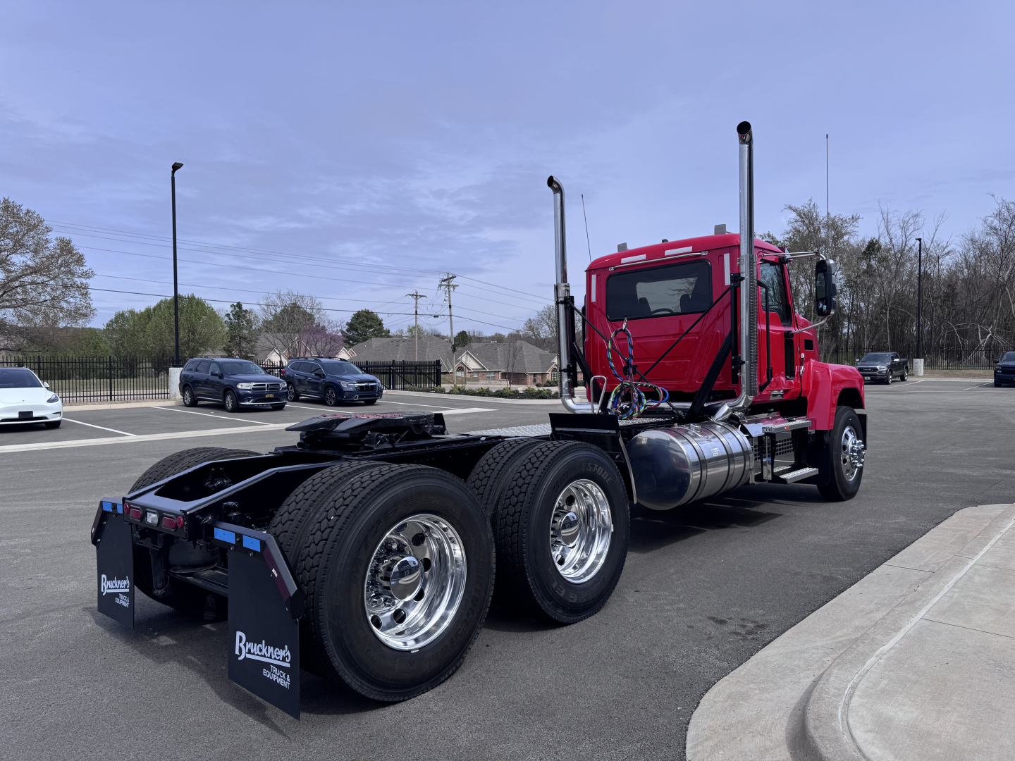 Mack PI64T truck rear/side view showing dual rear axles with chrome wheels and fuel tanks; red cab with tall exhaust stacks; no visible text on side panels.