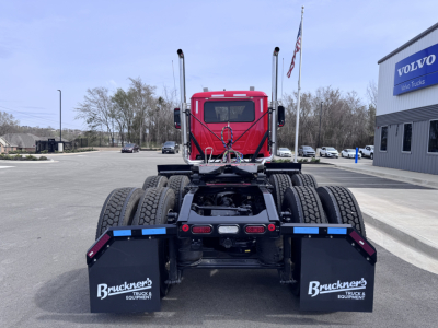Rear view of a red 2027 Mack PI64T daycab truck chassis showing dual rear axles, mud flaps with Bruckner’s Equipment logos, and cab with window.