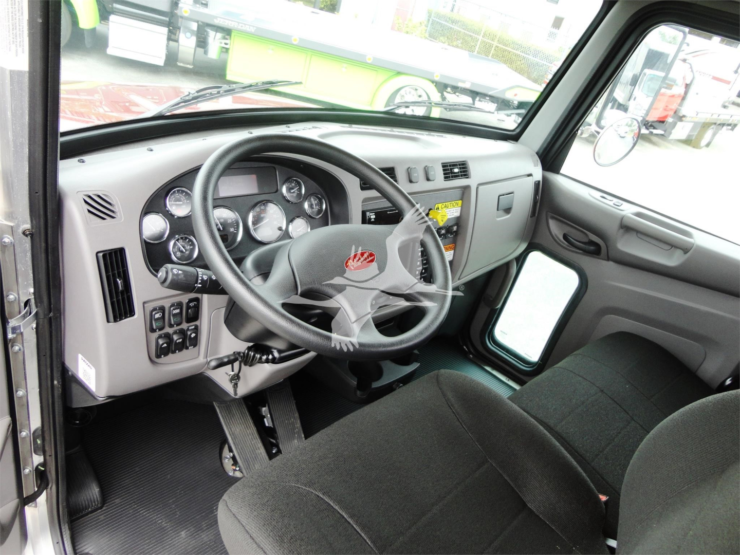 Truck cab interior of a 2022 Peterbilt 337 showing steering wheel, dashboard gauges, and driver seat.