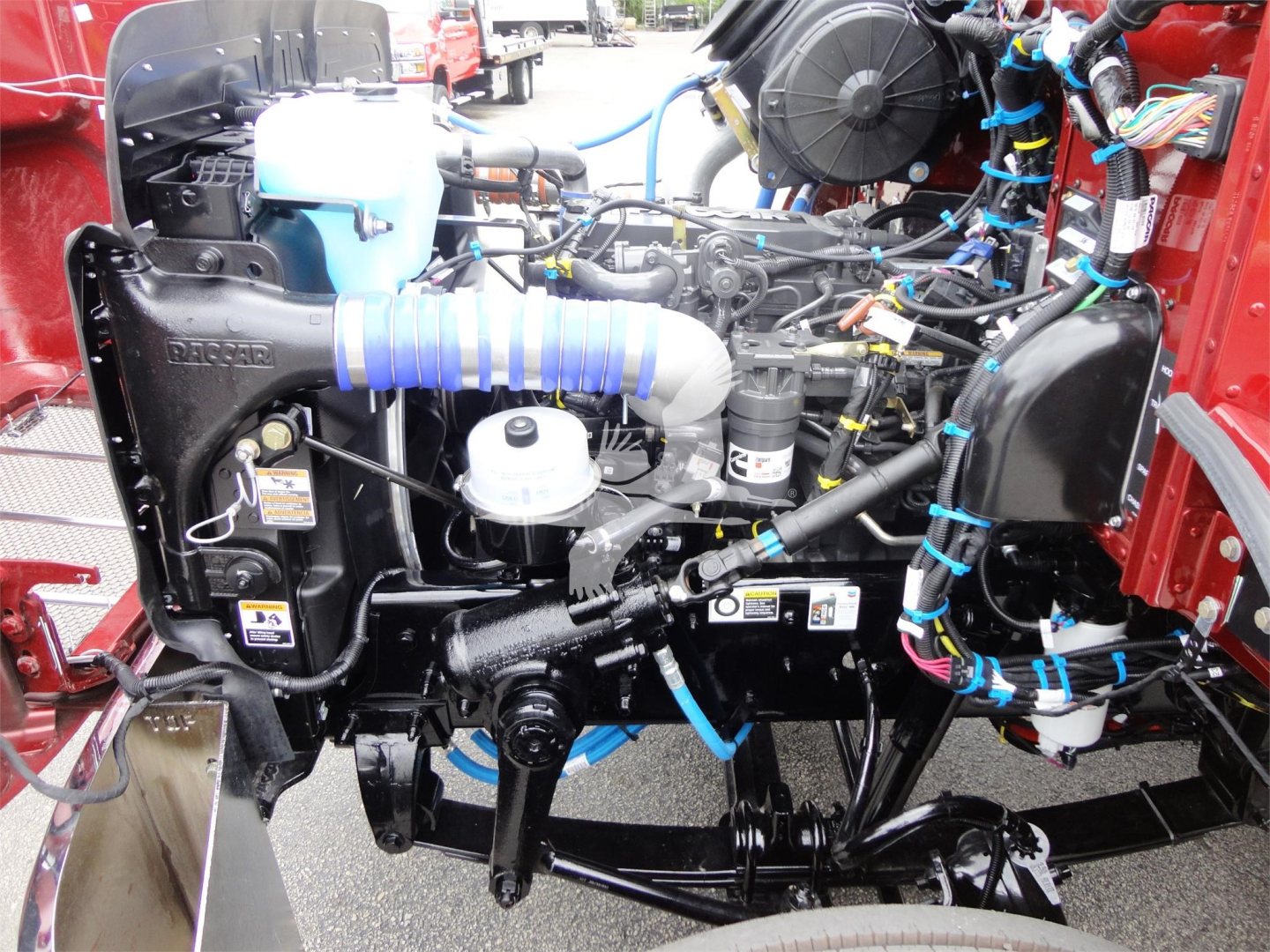 Peterbilt 337 engine bay with exposed components including radiator, hoses, belts, wiring harness, and air intake; multiple blue zip-ties and fluid reservoirs visible.