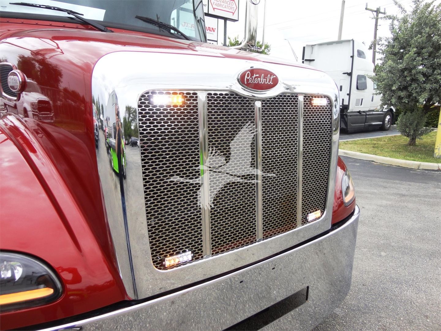 Peterbilt 337 front grille with chrome mesh, red cab, and amber marker lights.