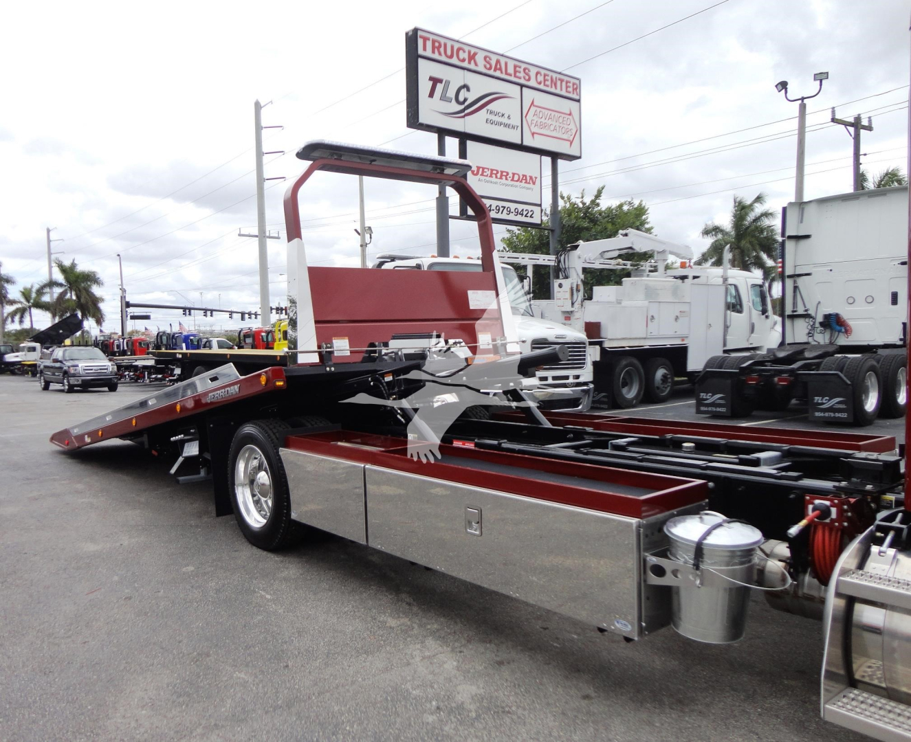 Peterbilt 337 rollback truck with flatbed and red hydraulic ramp, visible text includes TRUCK SALES CENTER TLC sign, and Jerr-Dan branding on equipment bay.