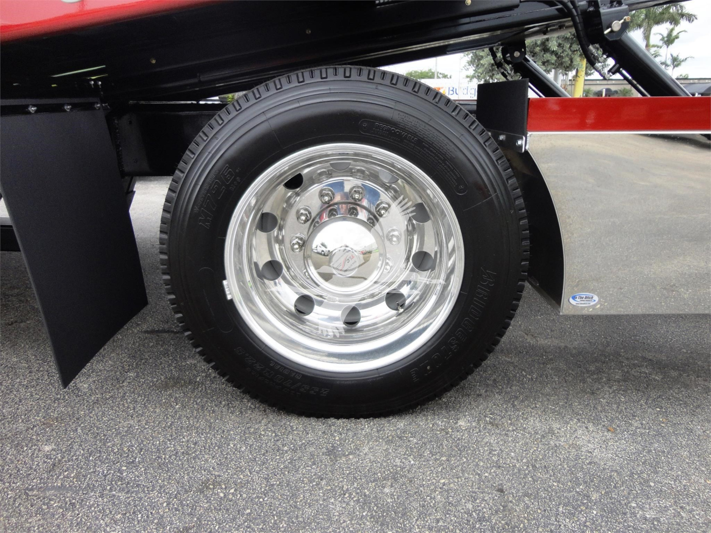 Peterbilt 337 rollback truck wheel and chrome hubcap visible with black tire and red body panel.
