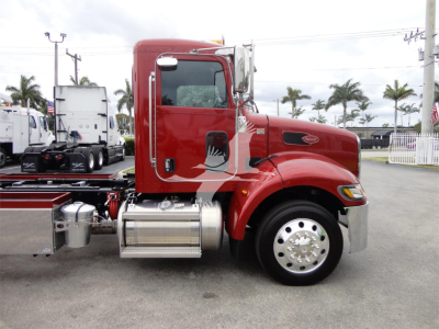 Peterbilt 337 rollback truck side view with red cab, chrome fuel tanks, and chrome wheels. No visible text other than small Peterbilt badge on the cab.