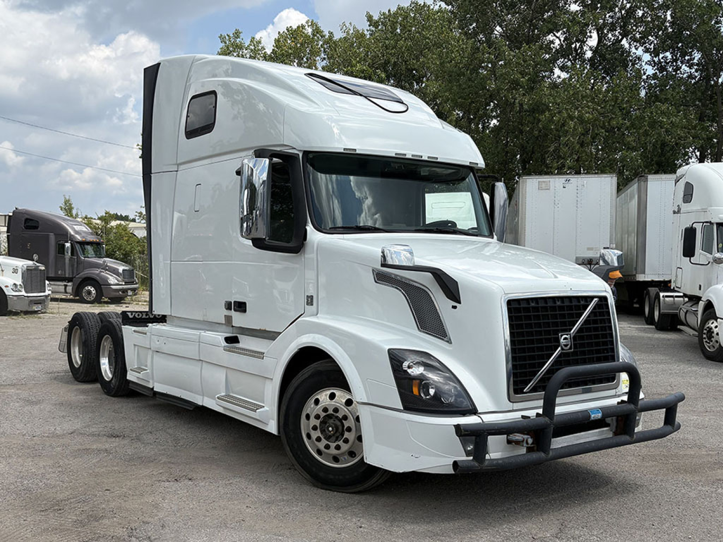Volvo VNL 670 tractor cab front and side view, white exterior with chrome mirrors and grille, bull bar bumper, sleeper cab with high roof.