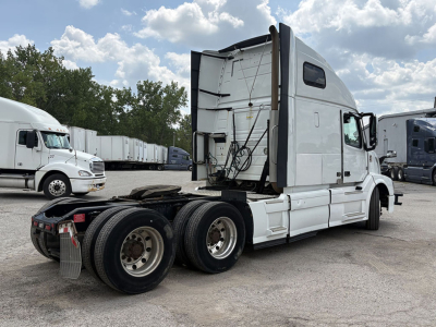 Volvo VNL 670 truck tractor in a yard, rear view showing fifth wheel, dual rear axles, and sleeper cab with rear vents.