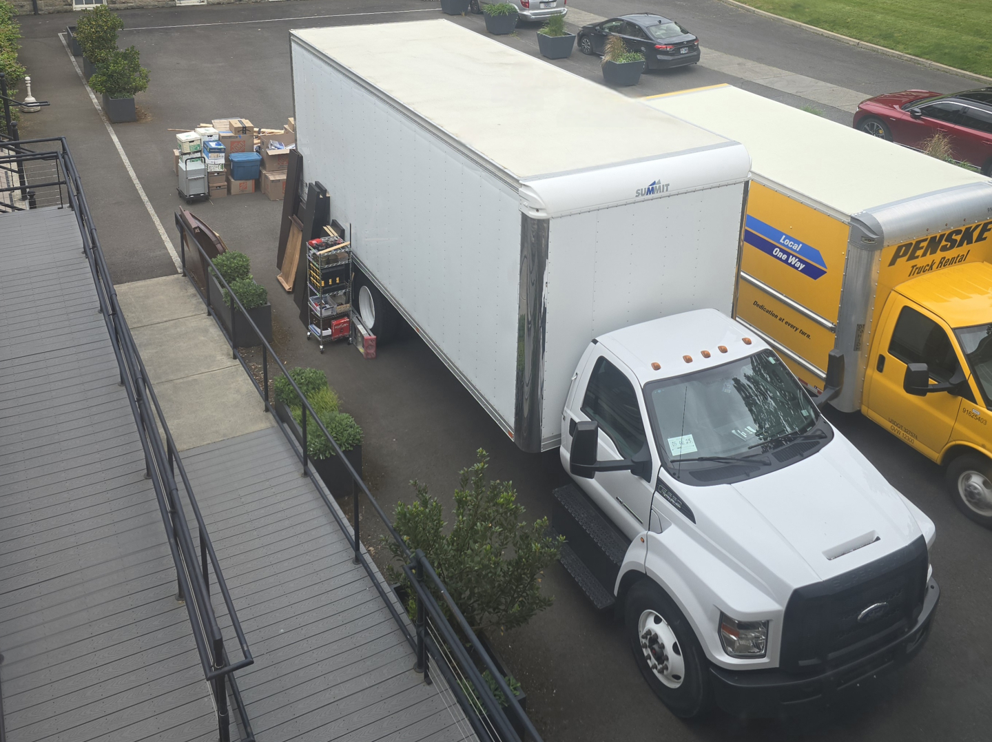 Truck configuration: white 2019 Ford 650 box truck with large cargo box, attached cab, alongside other box trucks and equipment in a lot.