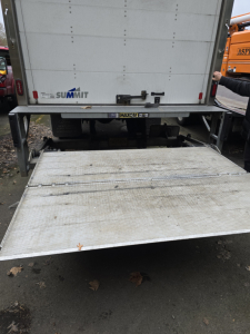 Rear view of a 2019 Ford 650 box truck with a lowered aluminum liftgate. VIN label visible, Summit logo on truck door, and Maxon branding on liftgate frame.