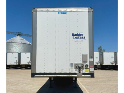 Rear view of a white trailer with Badger Express logo, built-in lights and rear bumper, in a dealership yard.