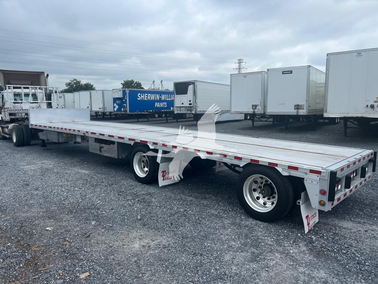 Dropdeck trailer showing extended flatbed with dual rear axles and aluminum decking