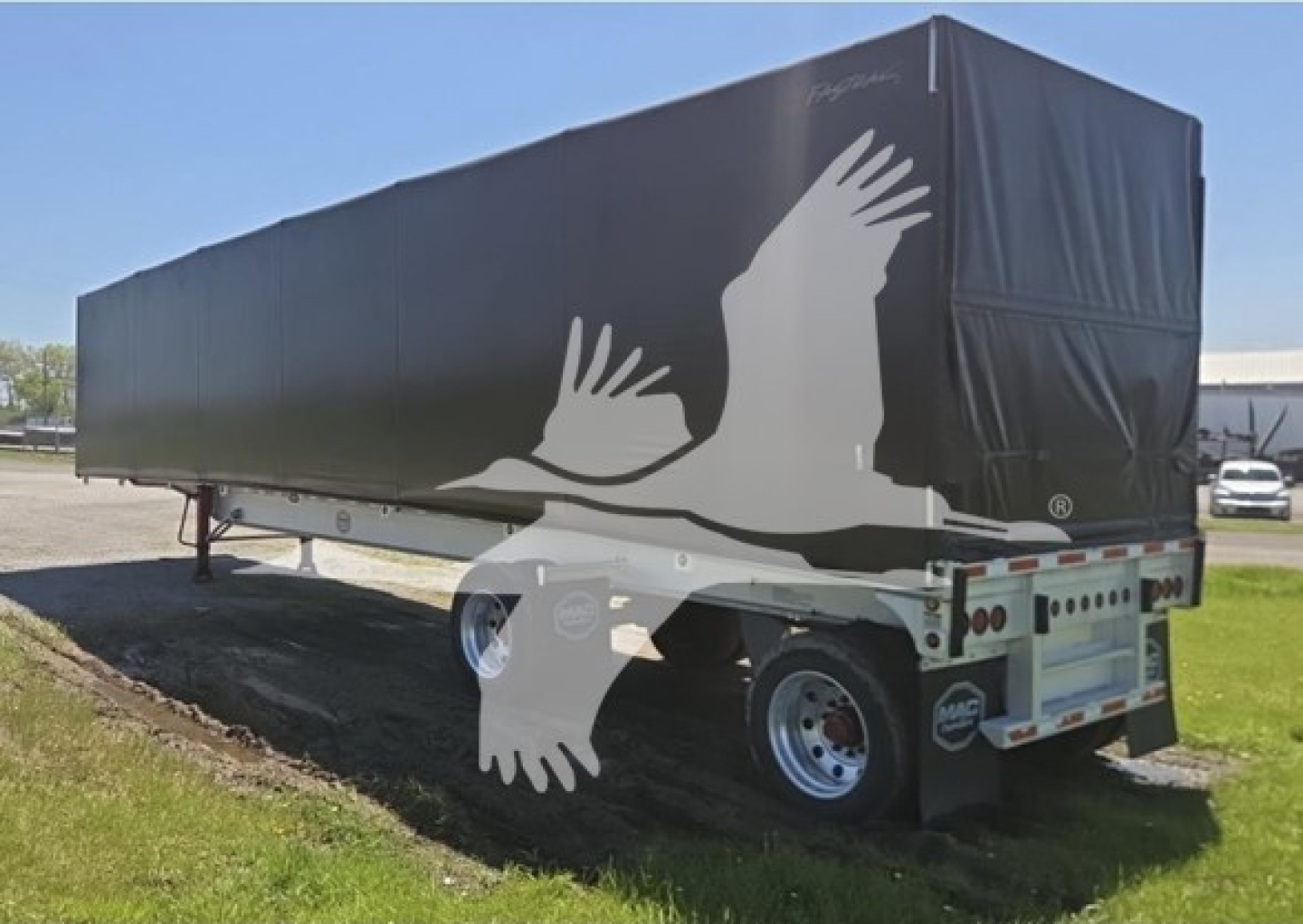 Mac aluminum flatbed trailer with 72K beam and roll tarp, side view showing Phoenix art on tarp and rear dual wheels.