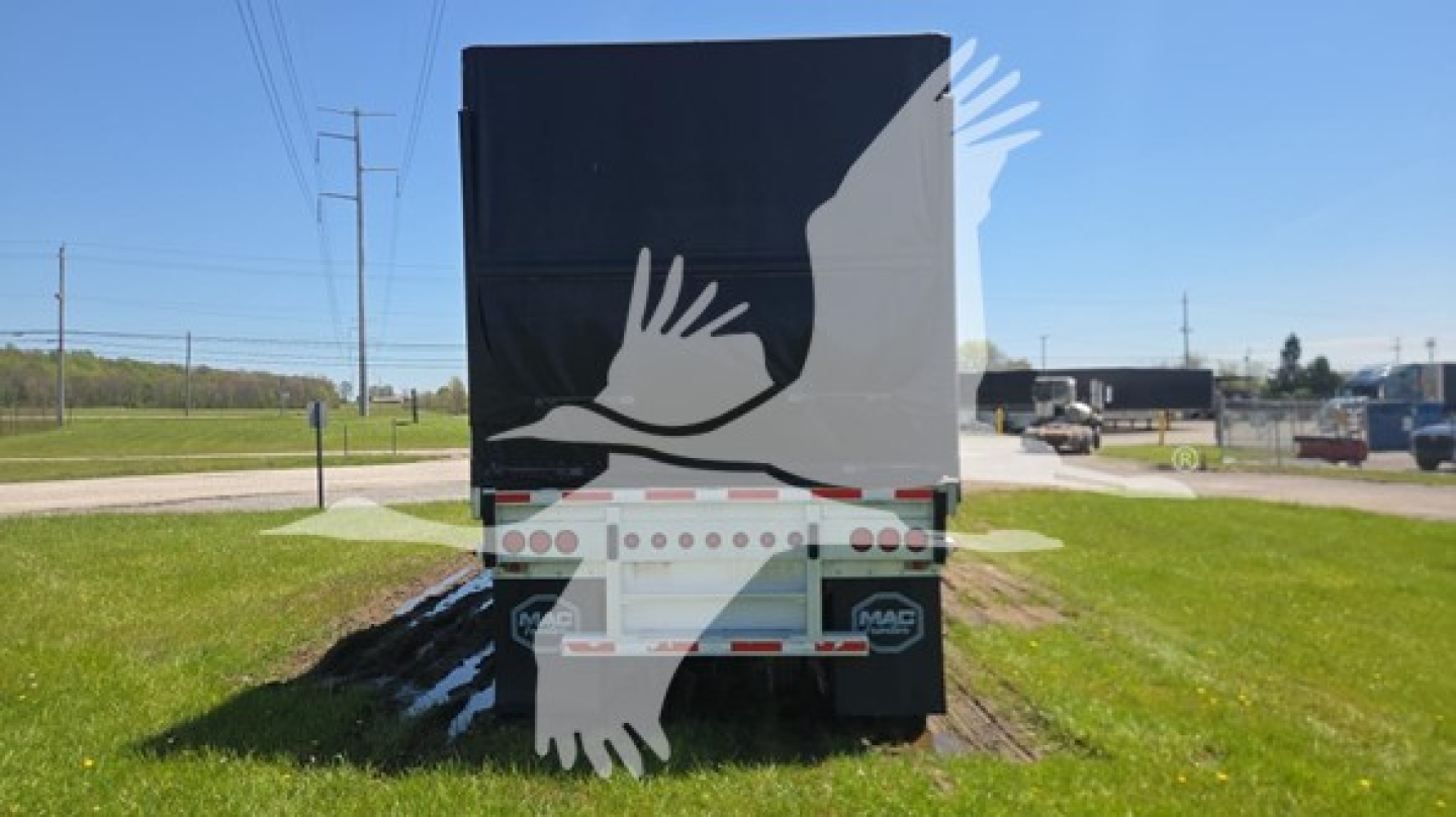 Rear view of a Mac aluminum flatbed trailer with a graphic of two white hands on a dark tailgate. Reflective safety decals and mud flaps visible.