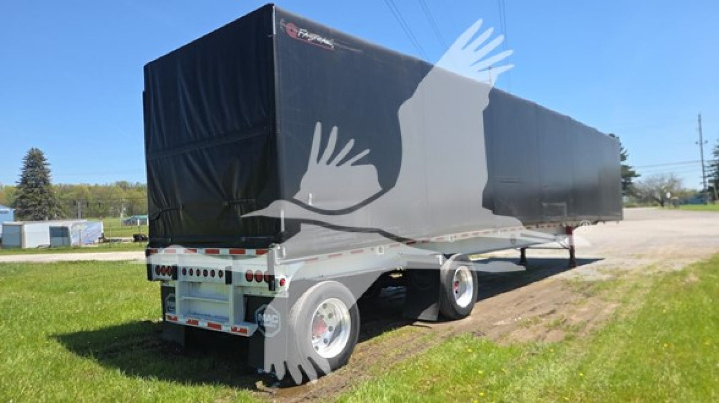 Flatbed trailer with black tarpaulin cover, dual rear axles, visible rear bumper and taillights.