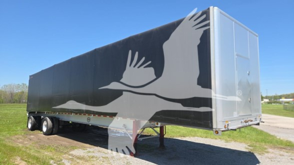Mac aluminum flatbed trailer 2013 with a large white bird graphic on side, curtainside trailer with twin rear axles, side view