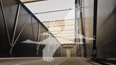Trailer interior showing aluminum flatbed beam with side rails and support structures inside a curtainside trailer.