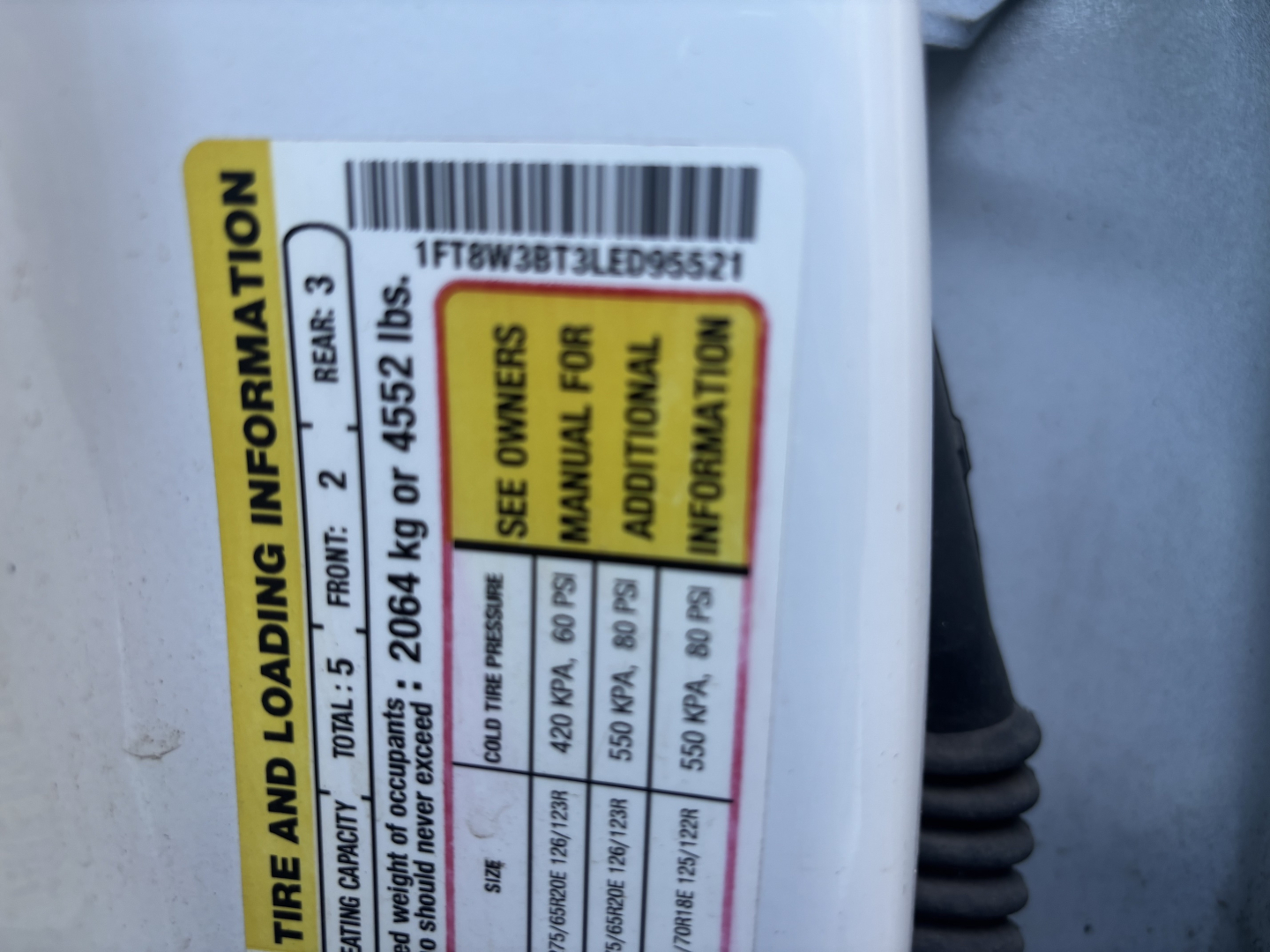 Ford F-Series cab and chassis VIN tag showing tire loading information and barcode sticker visible inside door jamb area