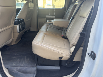 Ford F-350 cab and chassis interior, beige leather seats, rear bench, center armrest, captain seats, black rubber floor mats, visible back of front seats and rear seating area.