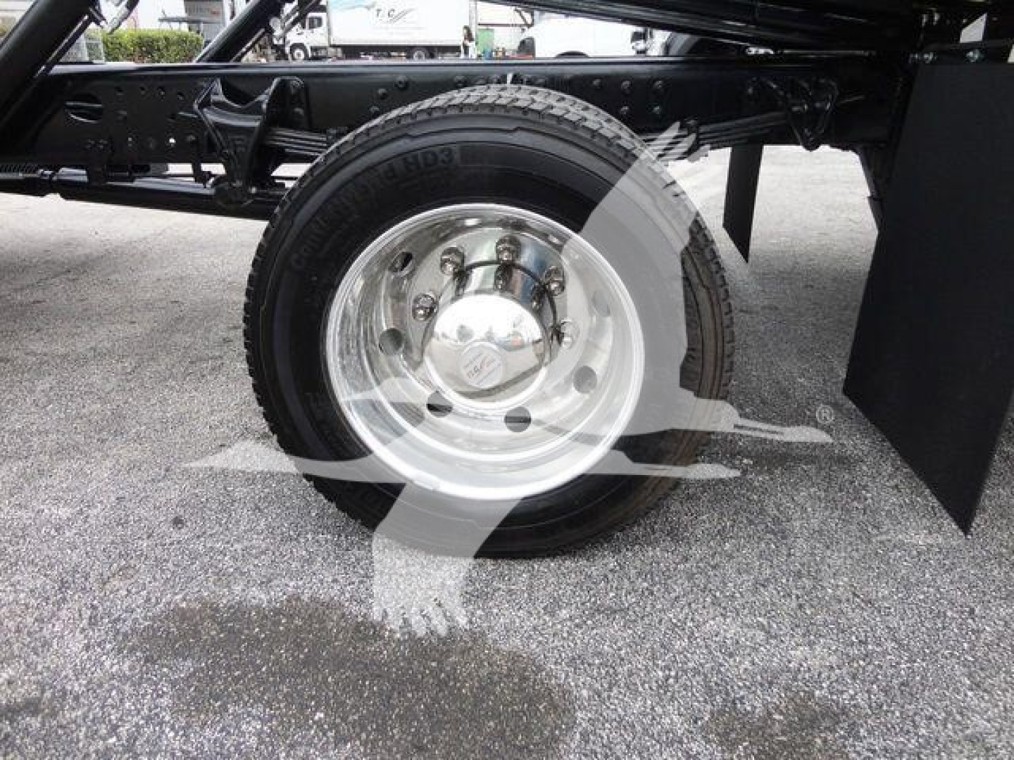 Truck wheel and suspension detail showing front axle with chrome hubcap and tire on a new 2023 International CV rollback truck.