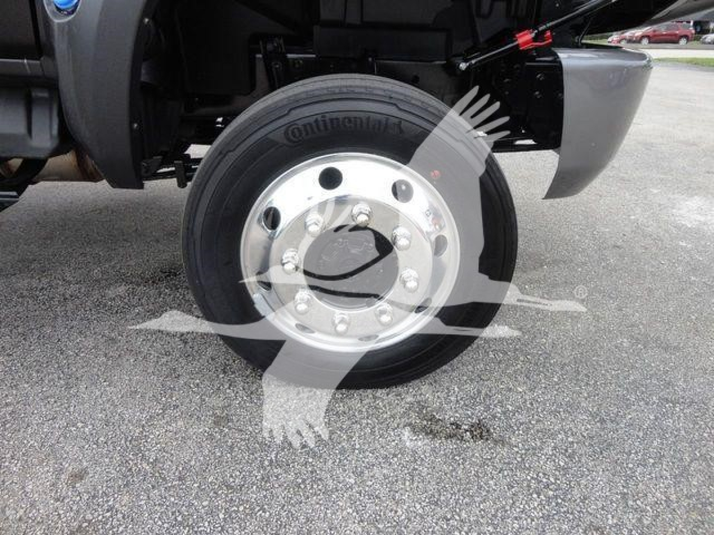 Truck wheel close-up showing Continental tire and polished metal hub with lug nuts, undercarriage components visible.