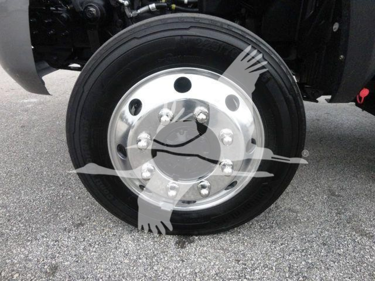 Front wheel of a heavy-duty truck showing a polished aluminum hub with multiple lug nuts and a black tire.