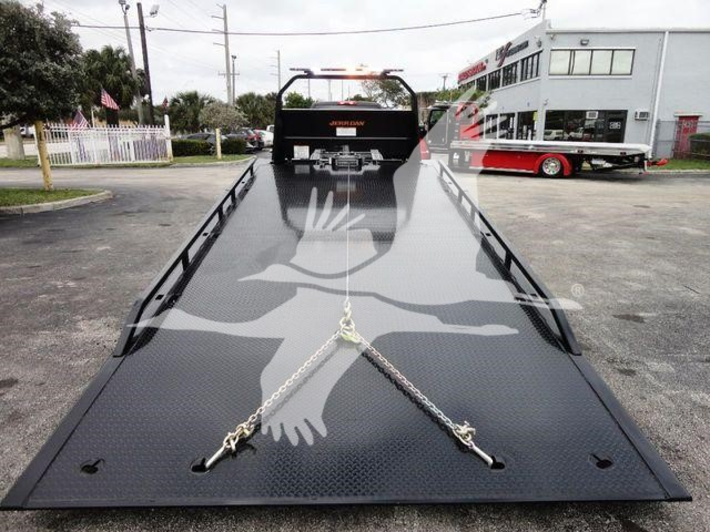 Tow truck rollback flatbed with safety chains and dash panels visible.