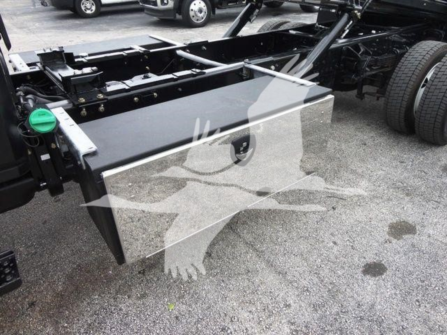 Truck chassis with large rectangular aluminum toolbox mounted, side view showing fuel tank cap and frame rails.
