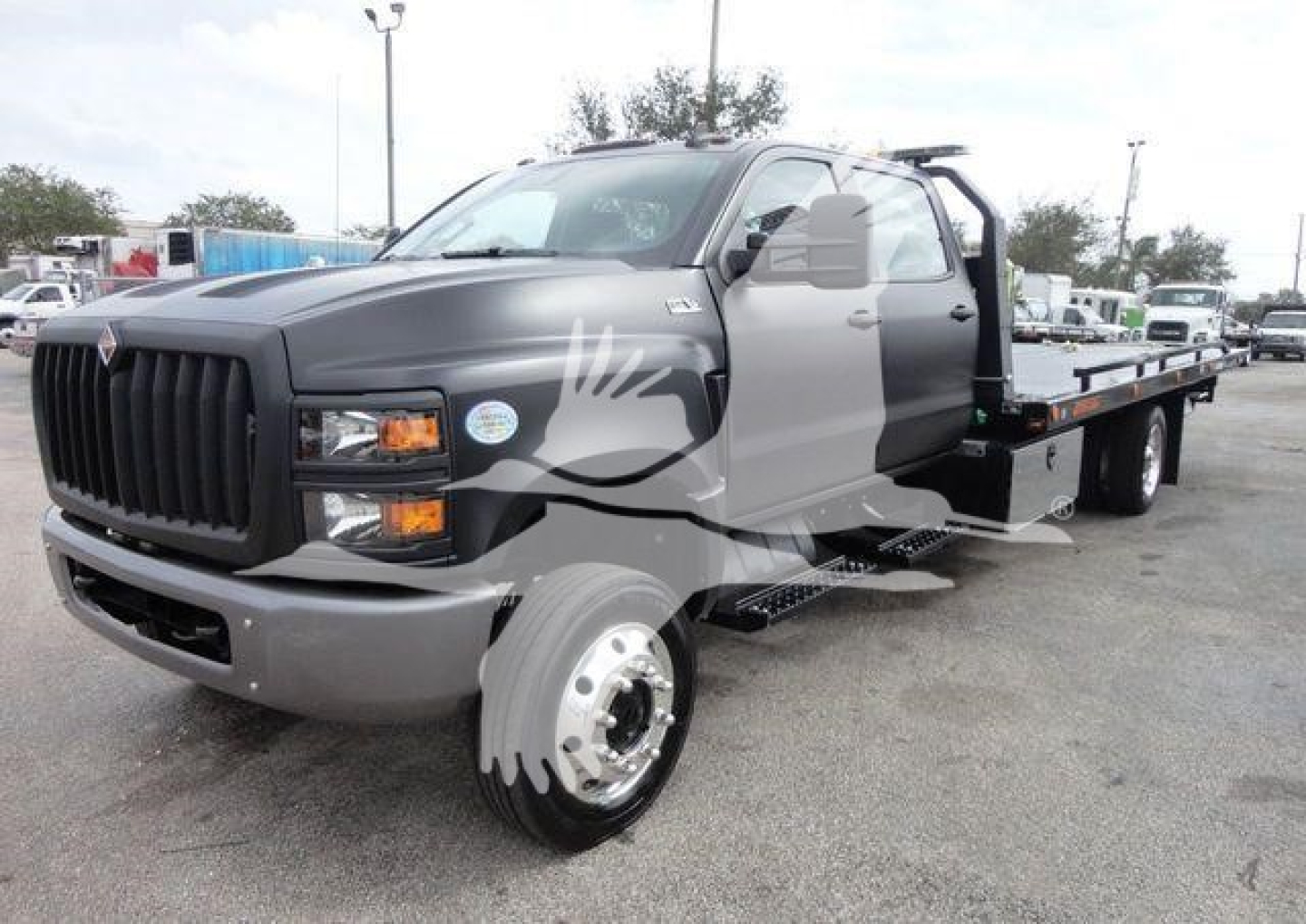 Truck showing flatbed rollback body with gray cab and black grille, International badge visible on front.