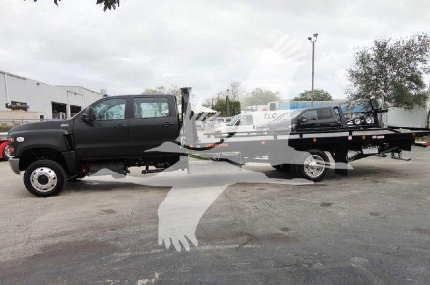 Truck with a rollback bed, black cab, side view showing long flatbed; no legible model text visible; image shows a two-axle truck with a ramp/bed setup.
