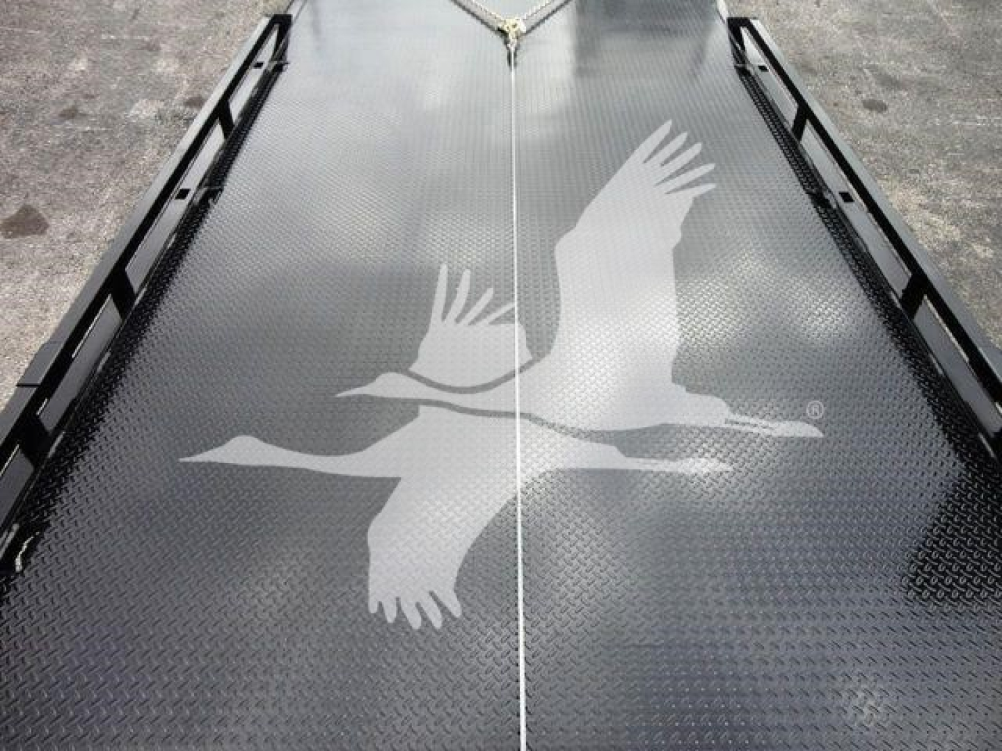 Platform with diamond plate surface and white gull silhouette graphic, central seam, and side rails.