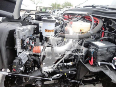 Truck engine bay showing coolant reservoir, brake fluid reservoir, and various hoses and wiring in a 2023 International CV rollback truck.