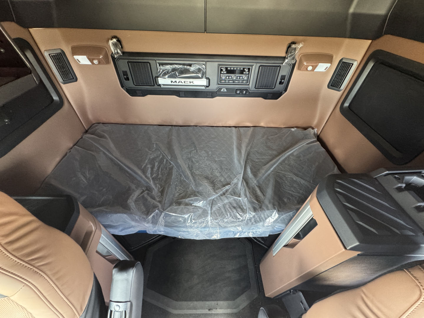 Mack AN64T64 truck cab interior showing dashboard with controls and beige upholstery.