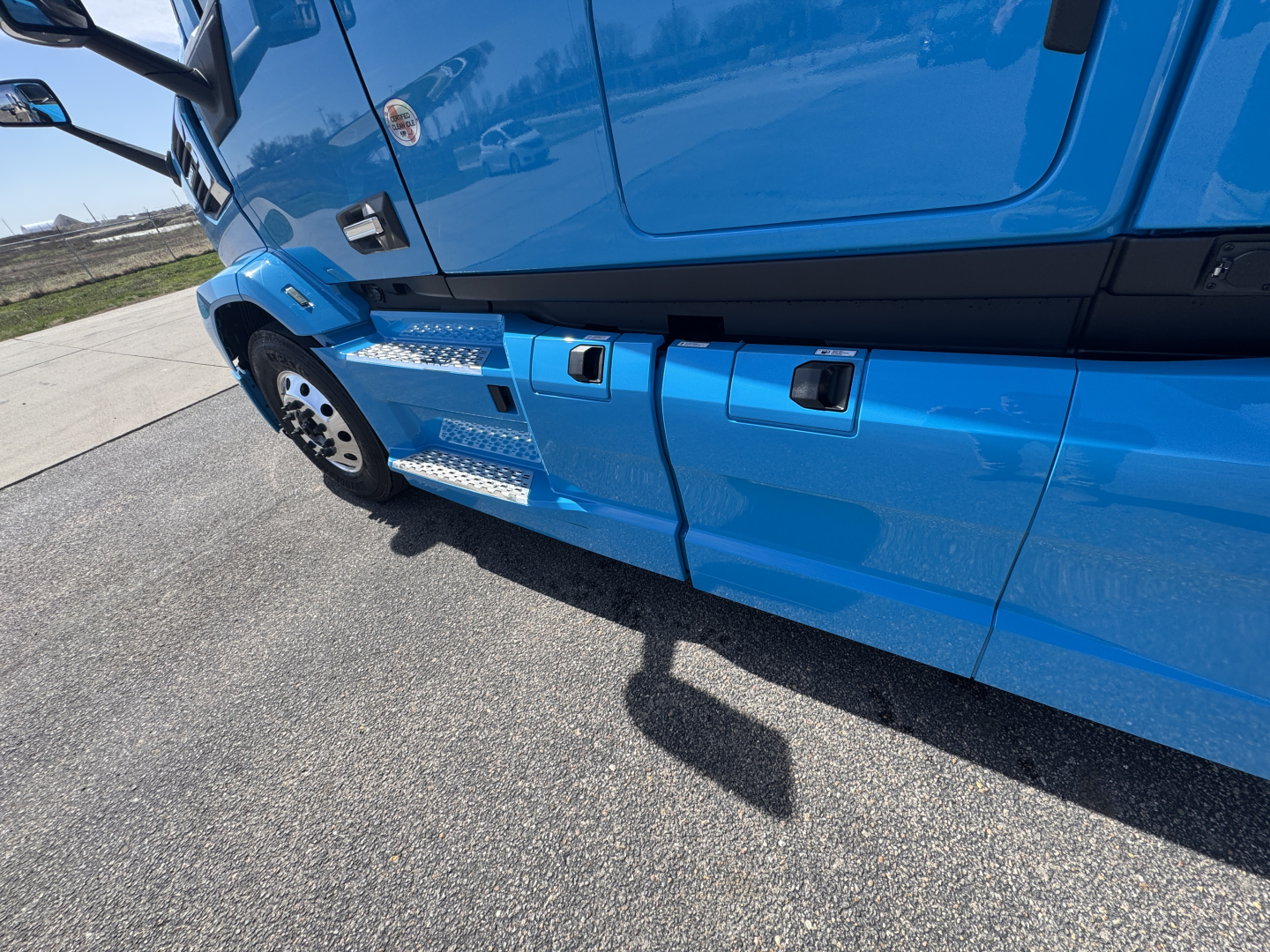 Truck side view showing blue Mack AN64T64 with metallic steps and door area; visible text includes part of the cab and wheel.