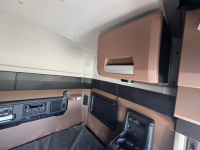 Interior cabin of a 2027 Mack AN64T64 sleeper showing brown leather panels, overhead storage, and controls on the dash area.