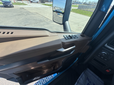 Truck cab interior door panel view showing window controls and beige trim.