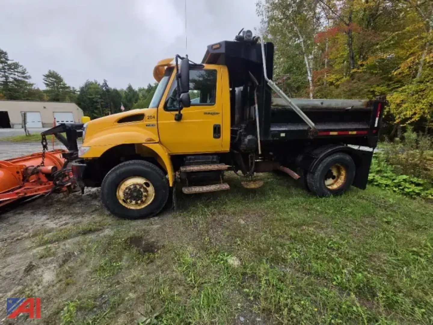 Dump truck showing yellow International 4300 with plow and wing, side view.