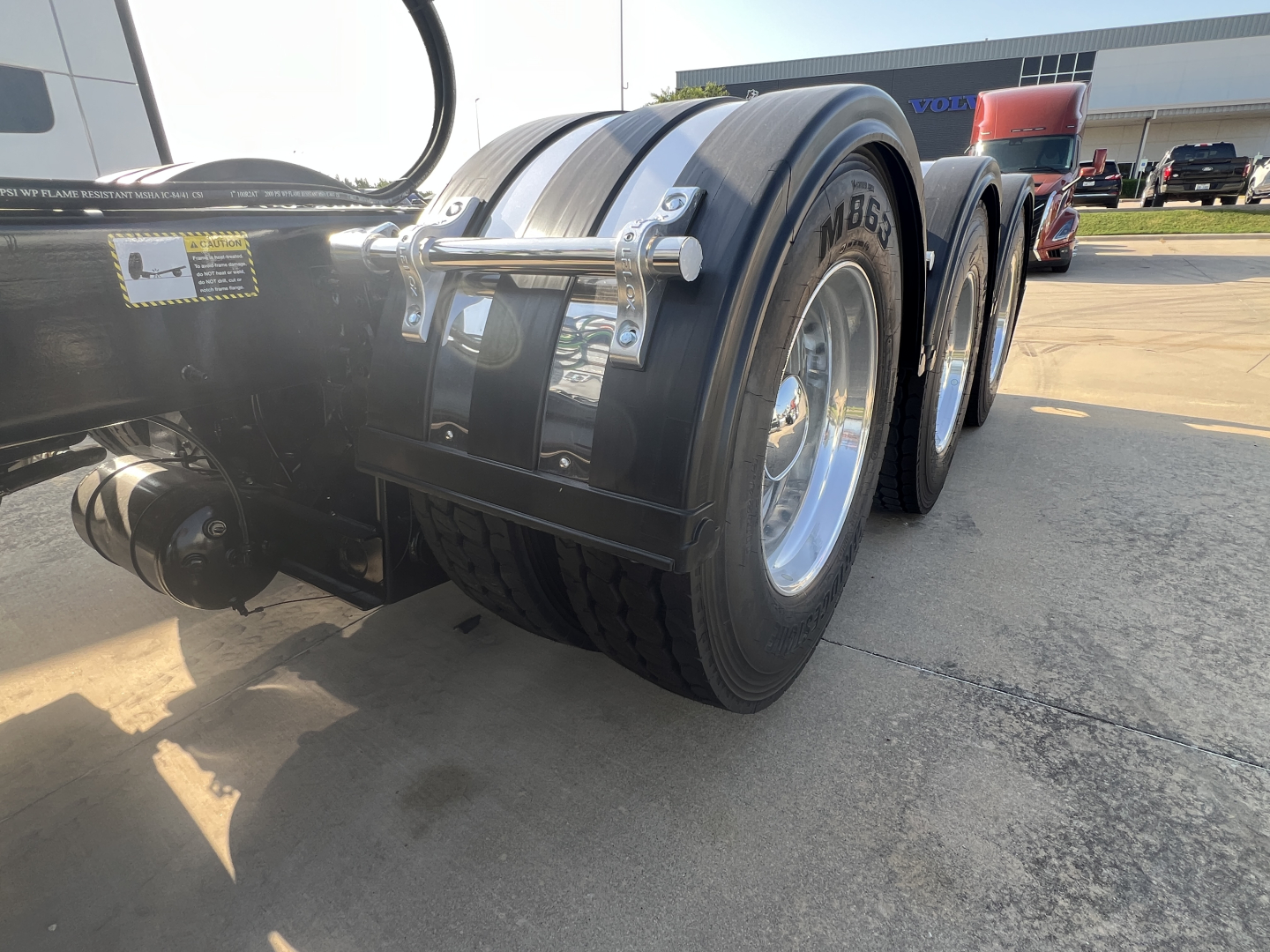 Truck rear axle and dual tires of a 2027 Mack GR84FT conventional daycab showing dual rear wheels and fenders.