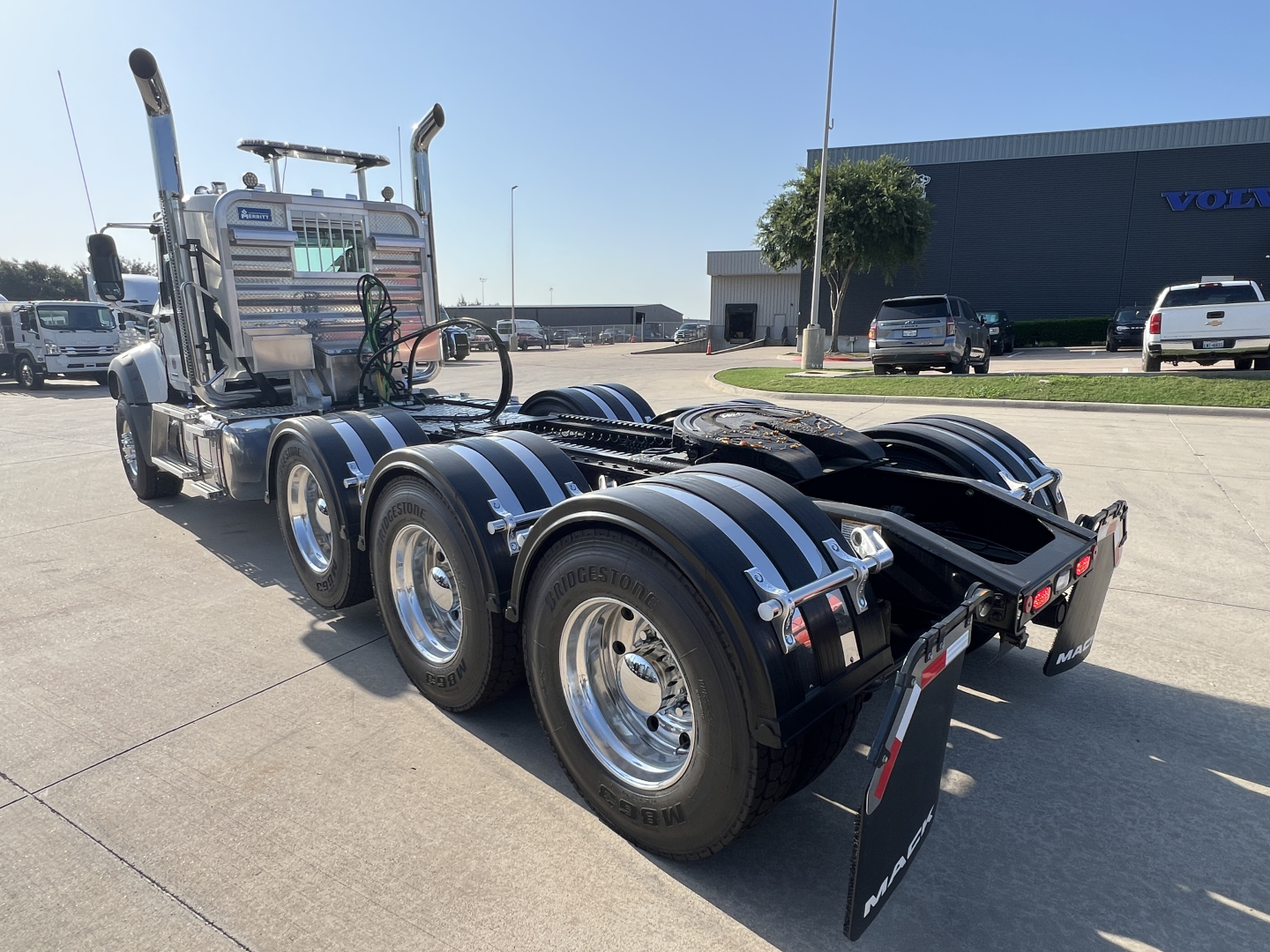 Mack GR84FT heavy-duty tractor rear and side view showing dual rear axles with chrome wheels and black fenders, fifth-wheel area, and vertical exhaust stacks.