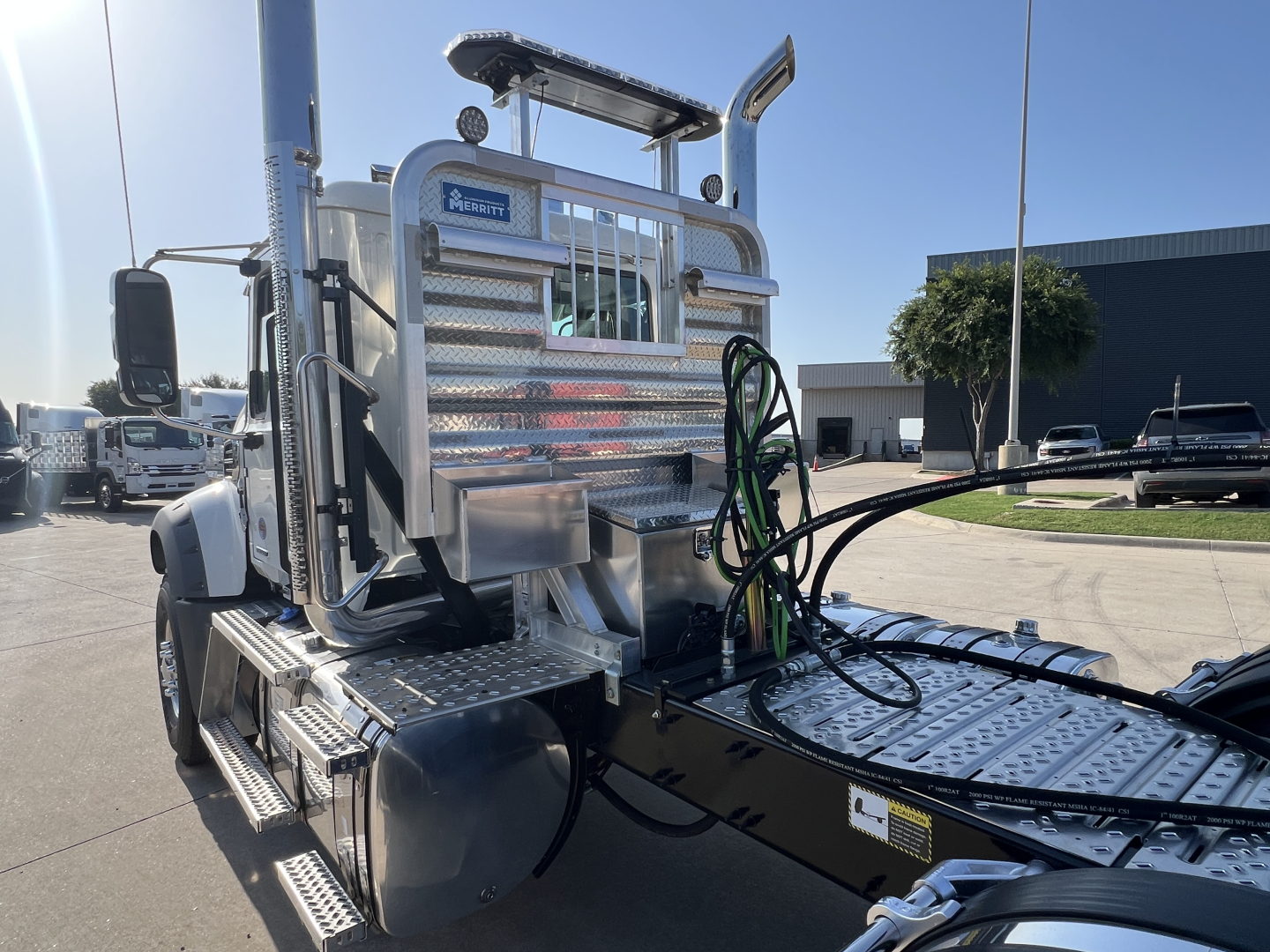 Mack GR84FT truck chassis showing aluminum fuel/utility tank, diamond plate steps, hoses, and cab access with chrome accents.