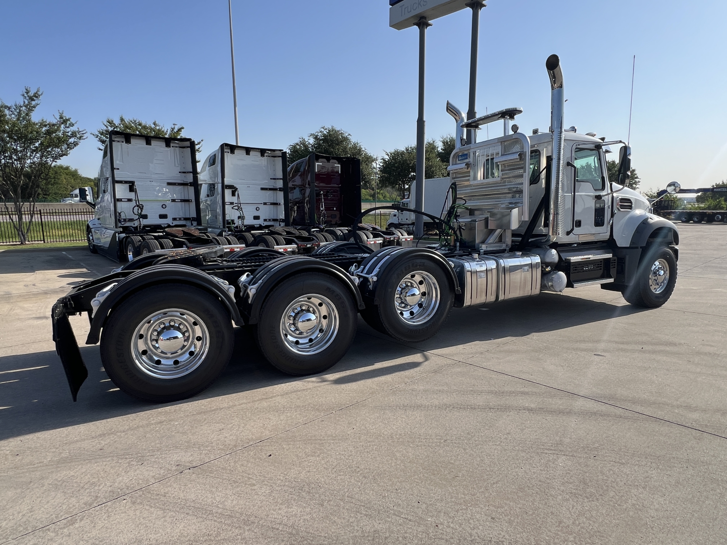 Truck chassis showing rear dual and tridem axle configuration and chrome fuel tanks.