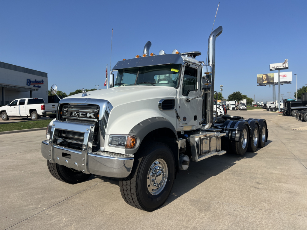 Truck: Mack GR84FT conventional day cab, side view showing chrome grille, dual exhaust stacks, large front bumper, tandem rear axles, fuel tanks, and warning lights.