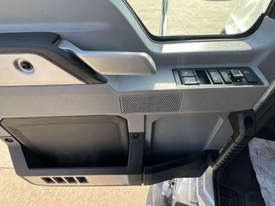 Cab interior of a new Mack GR84FT daycab showing door control panel, window switch cluster, and storage pocket.
