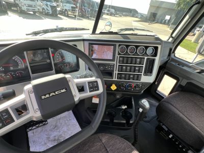 Mack GR84FT truck interior cockpit showing steering wheel with MAC logo, instrument cluster, multi-gauge panel, climate controls, and gear shifter.