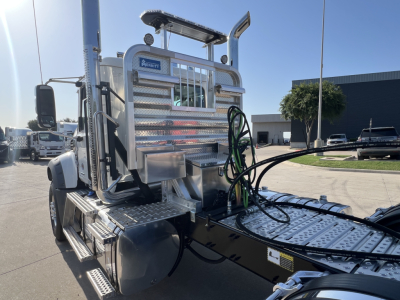 Mack GR84FT truck chassis showing aluminum fuel/utility tank, diamond plate steps, hoses, and cab access with chrome accents.