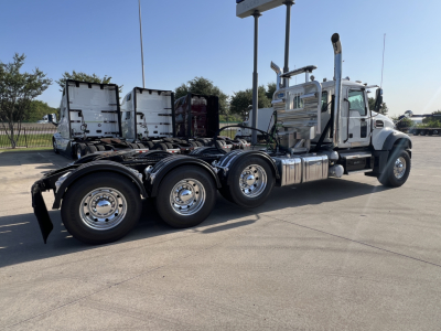 Truck chassis showing rear dual and tridem axle configuration and chrome fuel tanks.